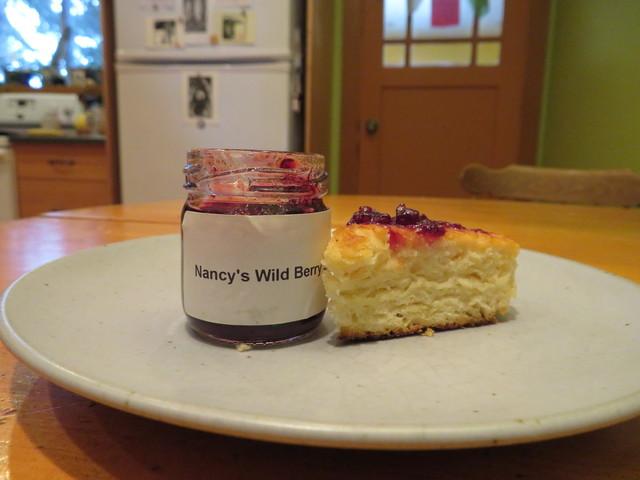Jar of jam next to bannock with jam. Label on jar says Nancy's wild berries.