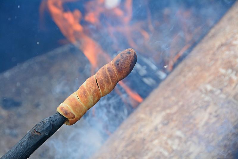 dough wrapped around a stick like a hot dog over a fire